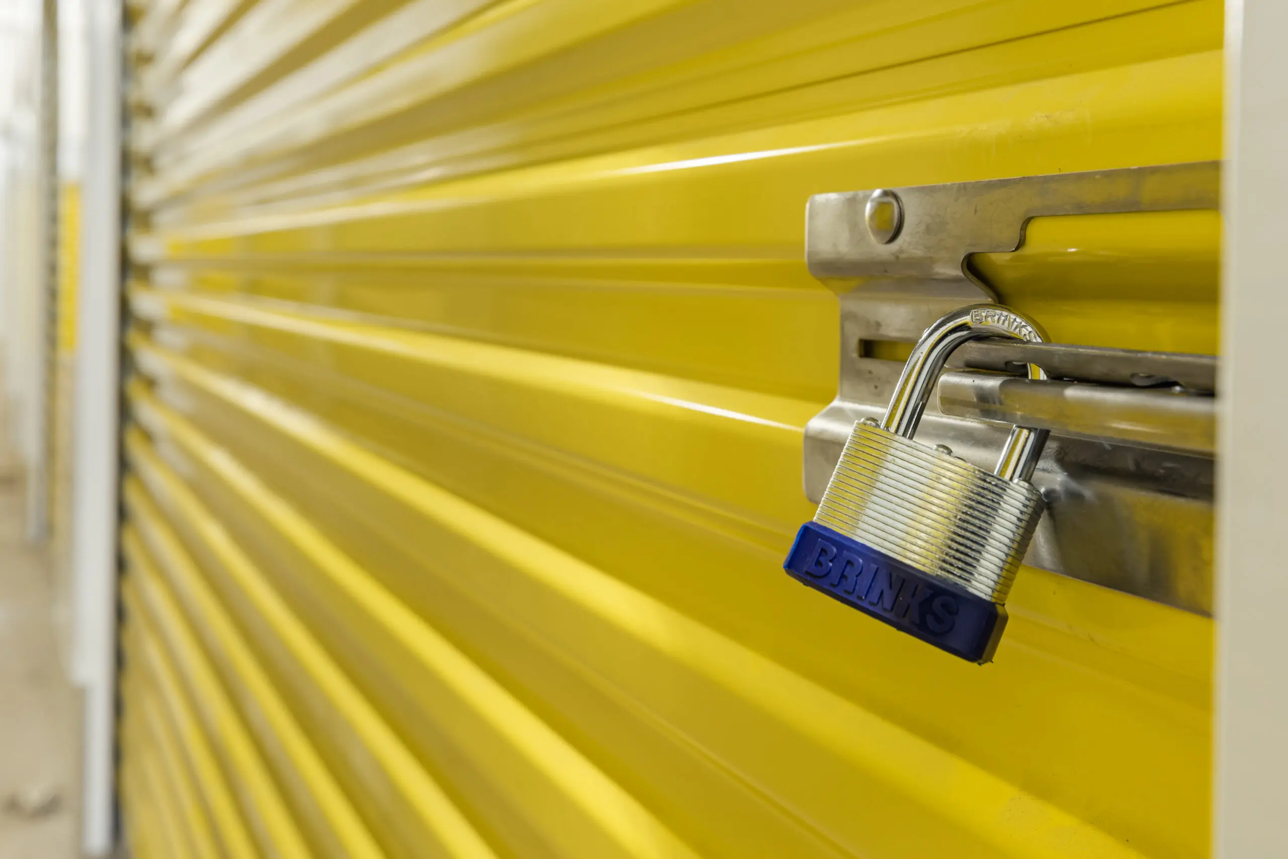 A close up of a padlock on the side of a yellow wall.